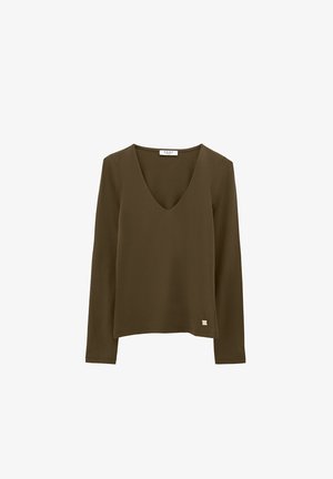 Camicia a maniche lunghe verde oliva con scollatura a V e piccolo marchio metallico vicino all'orlo, esposta su sfondo bianco.