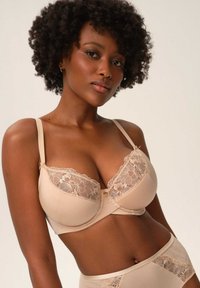 Beżowy zestaw bielizny z miękkiego materiału i koronkowymi akcentami. Biustonosz ma wsparcie podtrzymujące, koronkowe wykończenie i regulowane ramiączka.