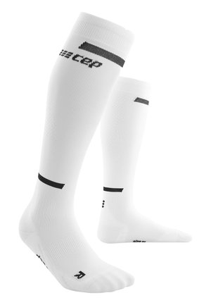 Calze bianche fino al ginocchio realizzate in un materiale liscio e elastico, con lettering del brand nero e righe orizzontali vicino alla cima.