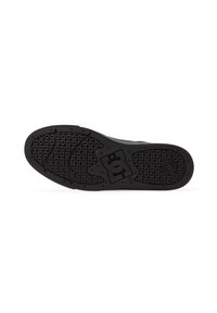 Black rubber sole of a sneaker featuring a patterned texture, embossed logo, and wavy tread for traction.
