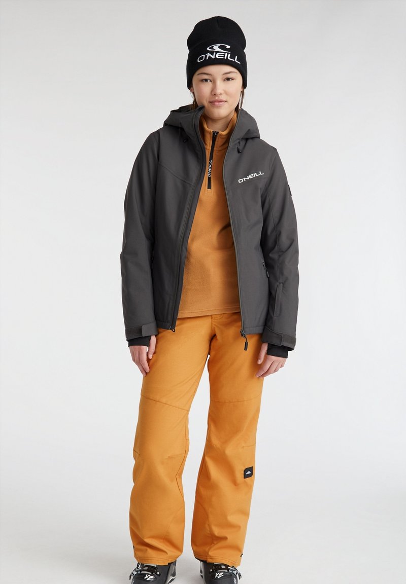 Czarna czapka beanie, szara kurtka zapinana na zamek, pomarańczowy polar i luźne pomarańczowe spodnie narciarskie. Zaprojektowane z myślą o aktywności na świeżym powietrzu, z logo O'Neill.