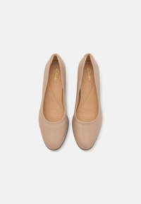 Beige bőr slip-on cipők lekerekített orral, perforált részletekkel a légáteresztés érdekében és sima, matt felülettel.