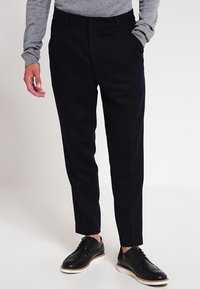 Tmavě námořnické kalhoty na míru z měkké látky, s plochým předním dílem, bočními kapsami a klasickým rovný střihem.