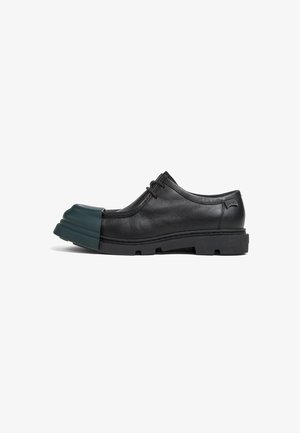 Scarpa in pelle nera con un distintivo puntale in gomma verde. Presenta un design a profilo basso, chiusura con lacci e una suola robusta per una buona aderenza.
