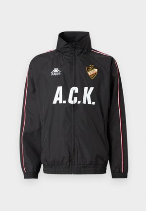 Schwarze Sportjacke mit Reißverschluss, weißem "A.C.K."-Schriftzug, Kappa-Logo auf der linken Brust, rot-weißen Streifen entlang der Ärmel und einem gelben Abzeichen auf der rechten Brust.