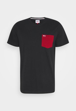 T-shirt noir à manches courtes avec une poche poitrine rouge et un petit logo rectangulaire dans le coin supérieur gauche de la poche.