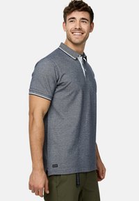 Grijze polo met een gestructureerde afwerking, contrasterende witte kraag en gestreepte accenten. Korte mouwen en subtiele logo-details aan de onderkant.