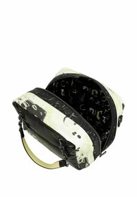 Sac de voyage à motifs noirs et blancs avec une fermeture éclair, doté d'un intérieur spacieux doublé d'un tissu sombre et d'une poignée accent jaune.