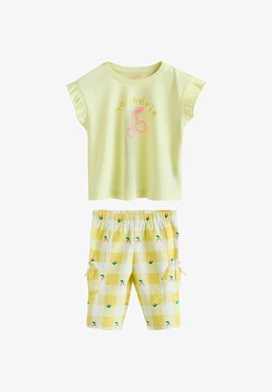 Žuti top kratkih rukava s naboranim rukavima i natpisom "ma chérie" te grafikom trešanja, u kombinaciji sa žutim šortsom sa kariranim uzorkom, cvjetnim printom i džepovima.