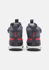 Zapatillas grises de media caña con acentos rojos, tejido texturizado, lengüetas de agarre y suela de goma negra. Presentan un collar y lengua acolchados.