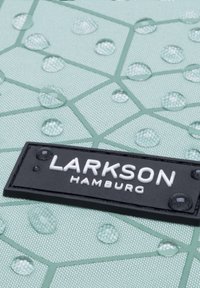 Zöld, textúrált szövet geometrikus mintázattal, vízcseppekkel. Egy fekete címke "LARKSON HAMBURG" felirattal, fehér betűkkel.