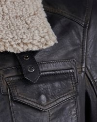 Zwarte leren jas met een crèmekleurige fleece kraag, drukknoopdetails en twee borstzakken met gestikte randen. Het gestructureerde materiaal is zichtbaar.