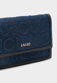 Portafoglio in denim blu navy con motivo a logo impresso, bordo nero a contrasto e una accentuazione in rosa oro del nome del marchio. Design a piegatura orizzontale.