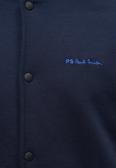 Καρδινάλιος σε ναυτικό μπλε με κουμπιά και μπλε κεντημένο λογότυπο "PS Paul Smith" στο στήθος.