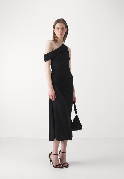 Rochie neagră, cu un umăr, cu decolteu drapat, design până la genunchi, realizată dintr-o țesătură netedă. Asortată cu sandale negre cu barete și o geantă mică.