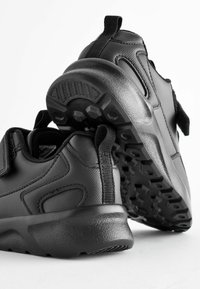 Chaussures de sport noires avec une tige synthétique texturée, une semelle en caoutchouc et un motif de semelle. Onglets de tirage à l'arrière pour un enfichage et un retrait faciles.