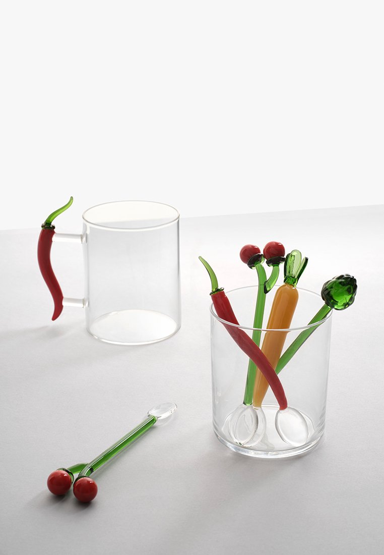 Przezroczyste szklanki z kolorowymi uchwytami w kształcie warzyw. Zawierają czerwone, zielone i pomarańczowe akcenty, przypominające różne papryki i pomidory.