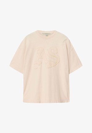 T-shirt oversize de couleur crème avec manches courtes et lettres "AS" en relief texturé sur le devant.