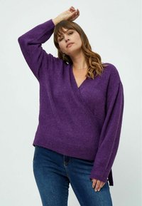 Violetinis apvyniotas megztinis su ilgomis rankovėmis ir V formos iškirpte. Pagamintas iš minkštos medžiagos, su laisvu siluetu ir šoninėmis sklendėmis patogumui.