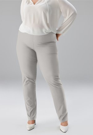 Hellgraue, dehnbare Hosen mit schmaler Passform, kombiniert mit einer weißen, locker sitzenden Bluse mit V-Ausschnitt und langen Ärmeln. Glatte Textur.