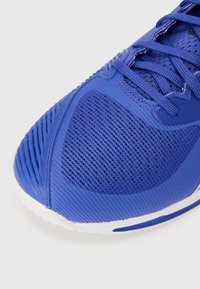 Blue athletic shoe featuring a textured mesh upper and a durable rubber sole. Laces are visible, providing a secure fit.