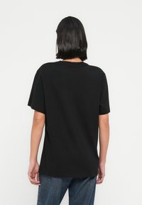 Μαύρο βαμβακερό T-shirt με  κοντά μανίκια και λαιμόκοψη στρογγυλή, με άνετη γραμμή και διακριτικές ραφές.