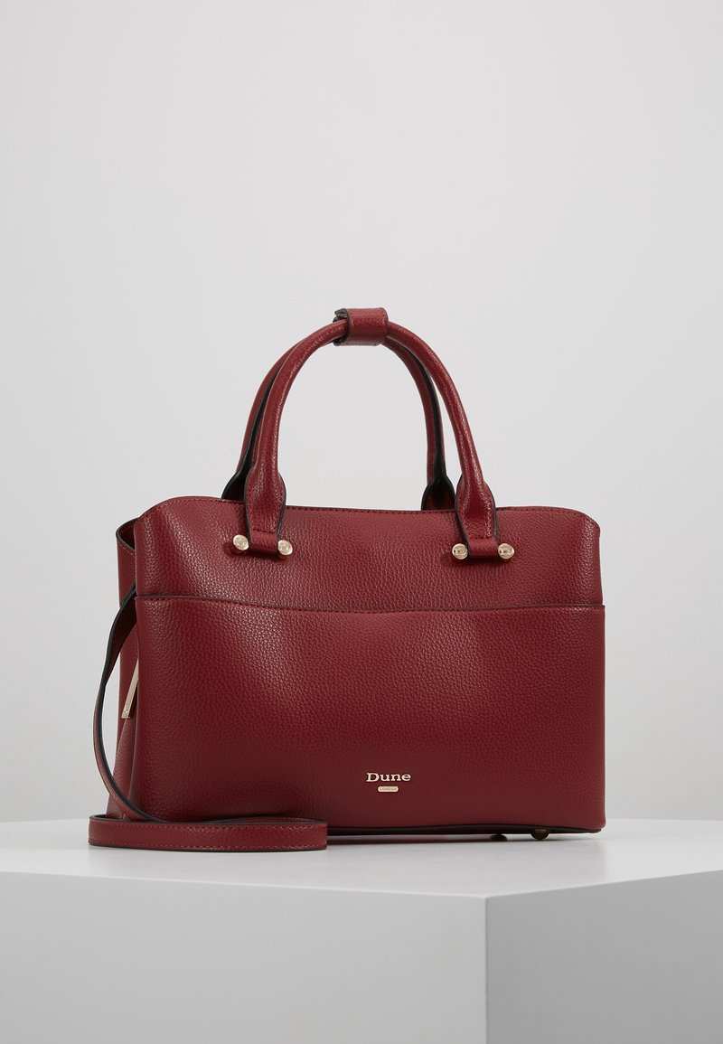 Rote Handtasche aus genarbtem Leder mit zwei Griffen, einem abnehmbaren Schulterriemen und goldfarbenen Akzenten. Verfügt über eine Fronttasche und gebrandete Metallbeschläge.