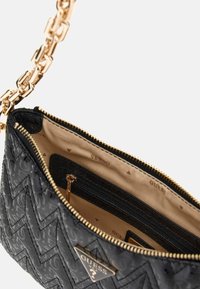 Sort mønsteret håndtaske med guldfarvet hardware, lynlås lukning og indvendige rum. Kædestrop tilføjer et elegant touch til den strukturerede ydre.