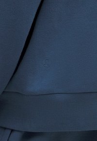 Felpa blu navy con tessuto testurizzato, orli e polsini a coste, e un sottile accento del logo tonale sul davanti.