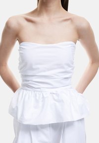 Hvid strapless top med en rynket bodice og en peplum flæse i kanten. Fremstillet af glat stof, med et minimalistisk design og rene linjer.