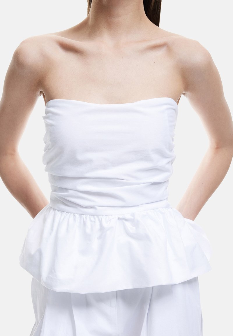 Hvid strapless top med en rynket bodice og en peplum flæse i kanten. Fremstillet af glat stof, med et minimalistisk design og rene linjer.