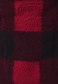 Red and black checkered fleece fabric with a textured, fluffy surface, featuring alternating solid squares in varying shades of red and black.