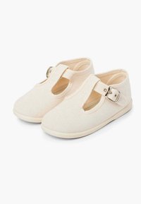 Scarpe per bambini color beige chiaro in materiale canvas, con design a T-bar e dettaglio con fibbia argentata. Punta arrotondata e suola morbida.