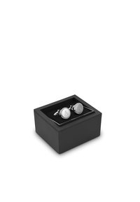 Srebrne spinki do mankietów o okrągłym kształcie, z teksturowaną krawędzią i wyrytym wzorem, zaprezentowane w czarnej pudełku z aksamitem w środku.