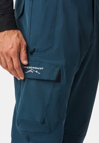 Pantaloni da esterno turchesi realizzati in tessuto morbido, con una tasca laterale con un accento nero e il logo bianco "SWEDEMOUNT".