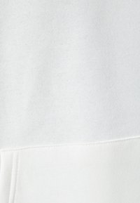 Tessuto di felpa bianca con una finitura morbida e texturizzata. Presenta un design completamente bianco, con un aspetto semplice e uniforme, senza decorazioni visibili.