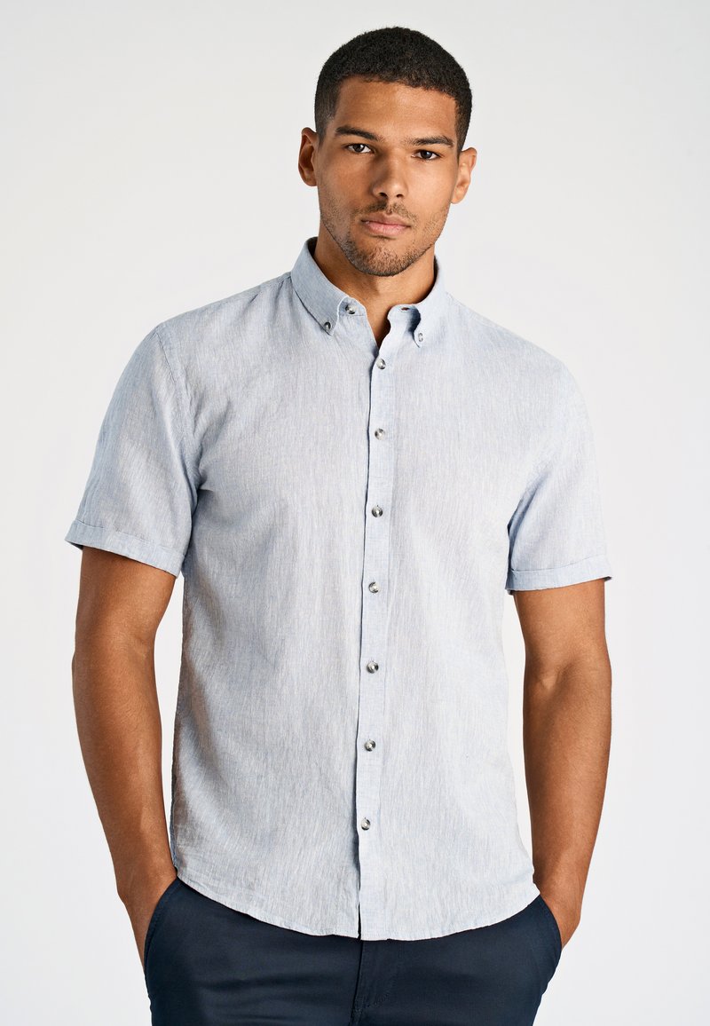 Jasnoniebieska koszula z krótkim rękawem zapinana na guziki, wykonana z teksturowanej tkaniny, z kołnierzykiem i srebrnymi guzikami z przodu. Regularny krój.