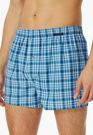 Blue and white checkered boxer shorts with elastic waistband, featuring a small embroidered logo, made from lightweight fabric.