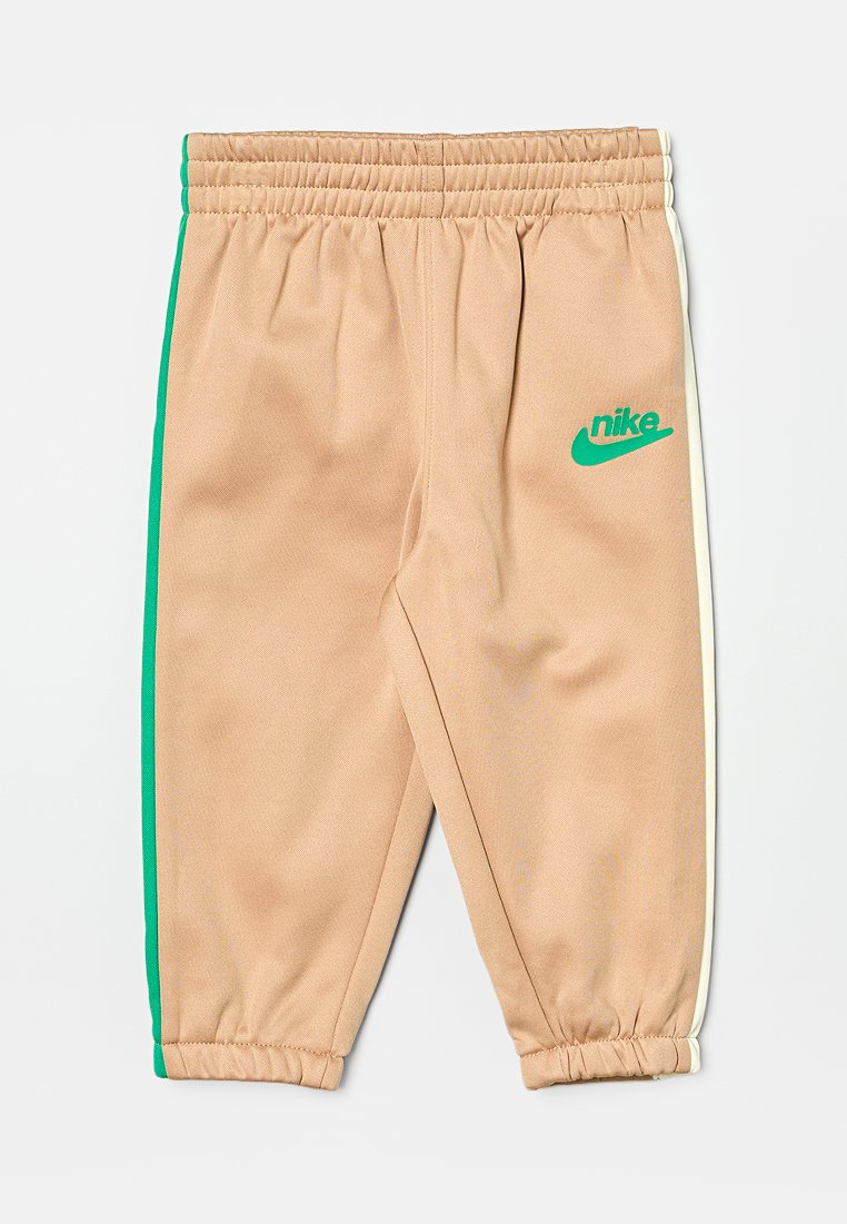 Beżowe dresy z bocznymi paskami w kolorze zielonym i białym, z elastycznym pasem w talii oraz małym zielonym logo Nike z przodu.