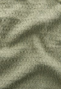 Tela verde texturizada con un patrón en relieve, que presenta un diseño ondulado y una sutil variación de tono, creando profundidad e interés.