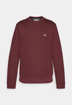 Sweatshirt en coton bordeaux à manches longues, col rond, avec des poignets et un ourlet côtelés ; présente un petit logo de crocodile brodé en vert sur la poitrine.