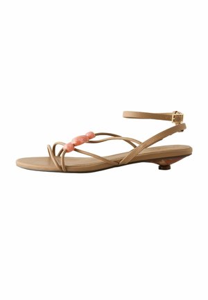 Nude strappy sandal with three coral-colored beads across the front and a low angled kitten heel with ankle buckle strap.