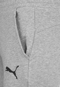 Grå sweatshirt med en känguruficka och en svart Puma-logga på vänster sida. Tillverkad av mjukt, texturerat tyg.
