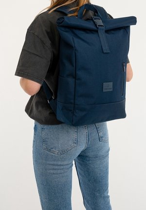 Zaino a roll-top blu navy con forma strutturata, texture in tessuto, tasca frontale con zip e patch con marchio sulla parte anteriore. Spallacci regolabili.