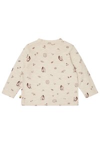 Lichtbeige langemouwen shirt met een speelse bruine bosdier- en natuurpatroon. Zachte textuur met een ronde hals en een afgeronde onderrand.