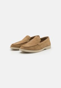 Brune suedeslippers med en glat tekstur, rund tå og beige gummisål. Minimal syning langs den øverste kant.