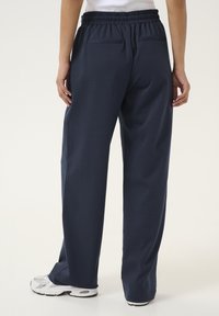 Navyblauwe, elastische taillebroek met een relaxte pasvorm, voorzien van twee achterzakken en een gladde, gestructureerde stof.
