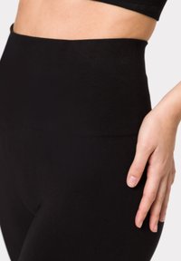 Leggings neri a vita alta con texture a righe. Tessuto morbido ed elastico che si adatta al corpo, caratterizzato da una finitura liscia e senza cuciture visibili.