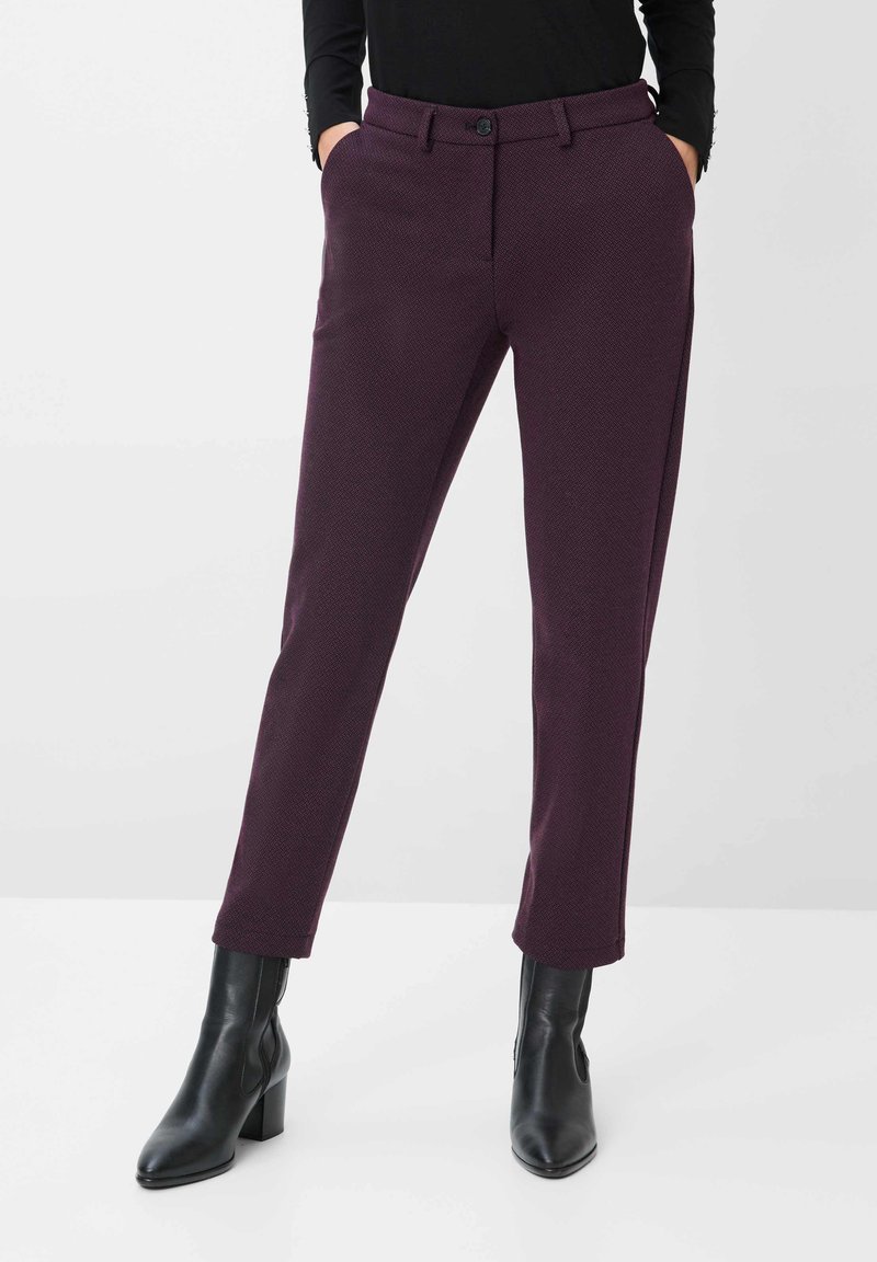 Violette, texturierte Hose mit schmalem Schnitt, ausgestattet mit einem Knopfverschluss und Seitentaschen, kombiniert mit schwarzen, hohen Stiefeletten.