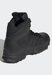 Botte de randonnée noire avec un dessus en cuir texturé et en mesh, col rembourré et semelle en caoutchouc présentant un motif à crampons pour une bonne traction.